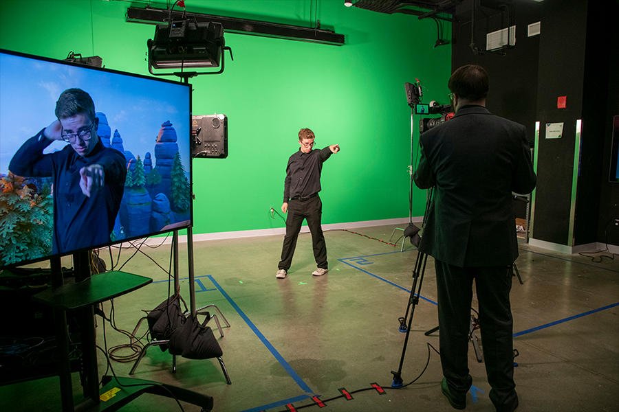 A guest poses in front of the green screen during a demonstration by the Film and Video Studies program at ARTS! By George 2022. (Photo by Cable Risdon Photography)