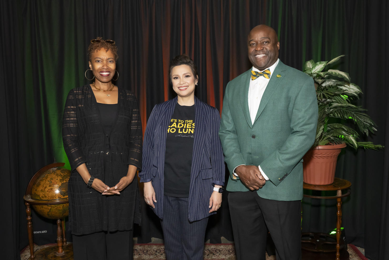 Two women stand with one man smiling towards the camera.