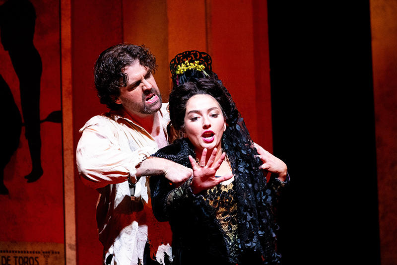 Zach Borichevsky as Don Jose, in a white shirt angrily holds Lisa Marie Rogali as Carmen, in a black dress and headpiece in the Virginia Opera's production of Carmen.