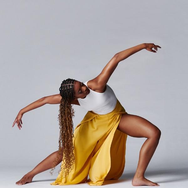 Fall New Dances - Mason dancer in yellow and white doing deep knee bend with arms raised