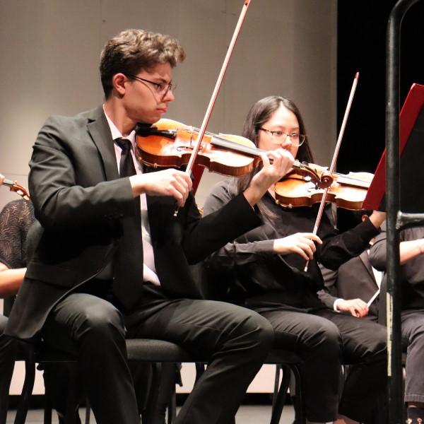 Mason Concert Orchestra students dressed in black, seated playing violins