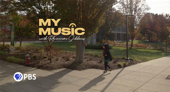 Title shot from PBS episode of "My Music with Rhiannon Giddens," showing Silkroad Ensemble pipa player Wu Man walking on the sidewalk towards the Center for the Arts at George Mason University.