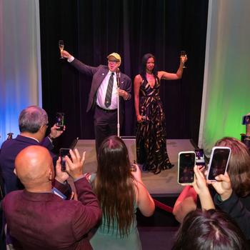 Renée Elise Goldsberry and Rick Davis lead a champagne toast on stage.