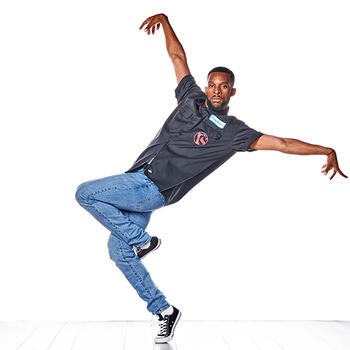 A street dancer from Versa-Style Street Dance Company poses, left foot locked behind his right knee. his